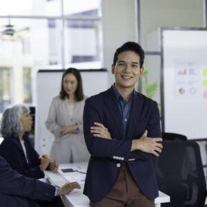 Asian businessman smiling with arms crossed during a meeting in the office