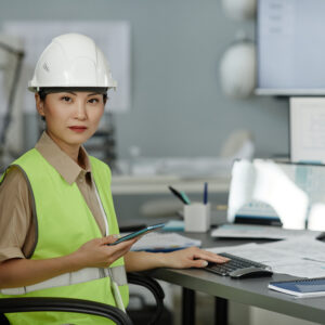 Asian woman wearing hardhat at workplace in office and looking at camera