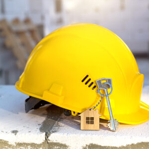Construction yellow hardhat and key to house on window of housin