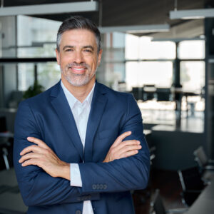 Happy middle aged business man ceo standing in office arms crossed. Portrait